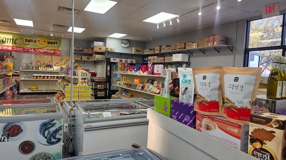 Inside Smile Mart: shelves of snacks, coffee and gift boxes behind a row of chest freezers, chili pepper chips in front